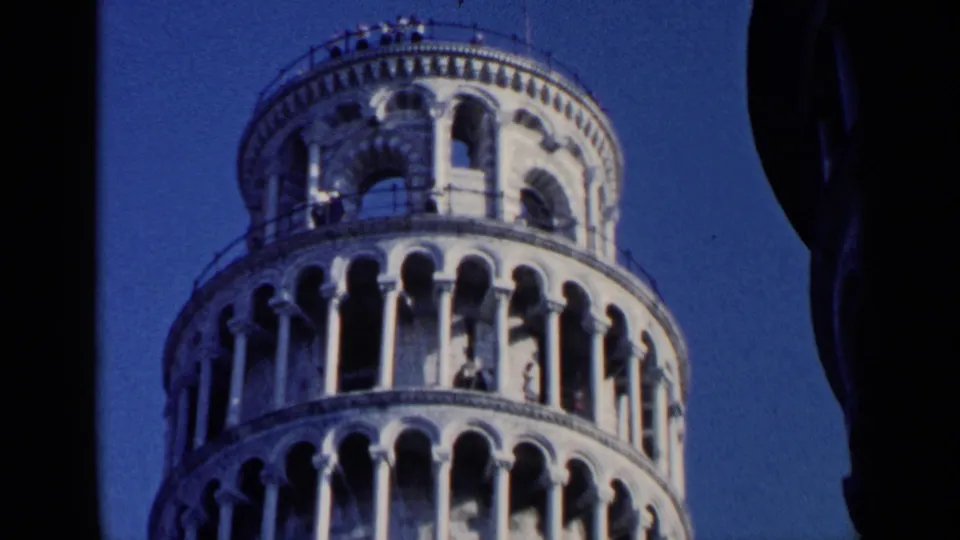 1960 8mm travel frame showing the top of the Leaning Tower of Pisa, including railing, arched openings, and sky.