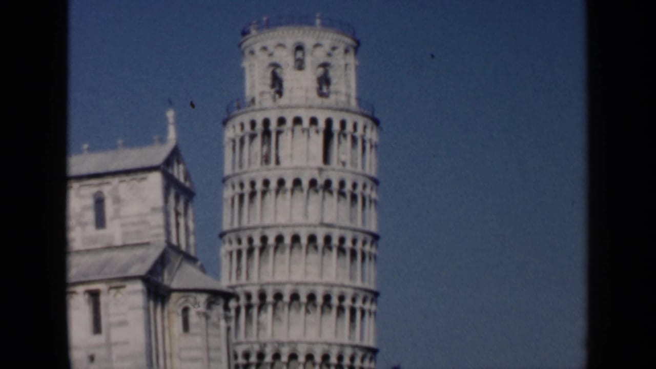 Leaning Tower of Pisa beside cathedral stonework under a blue sky.