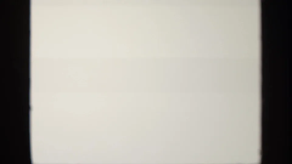 Final 8mm frame appears nearly blank, with pale exposure, dark film borders, and faint physical-film texture after the tower footage.