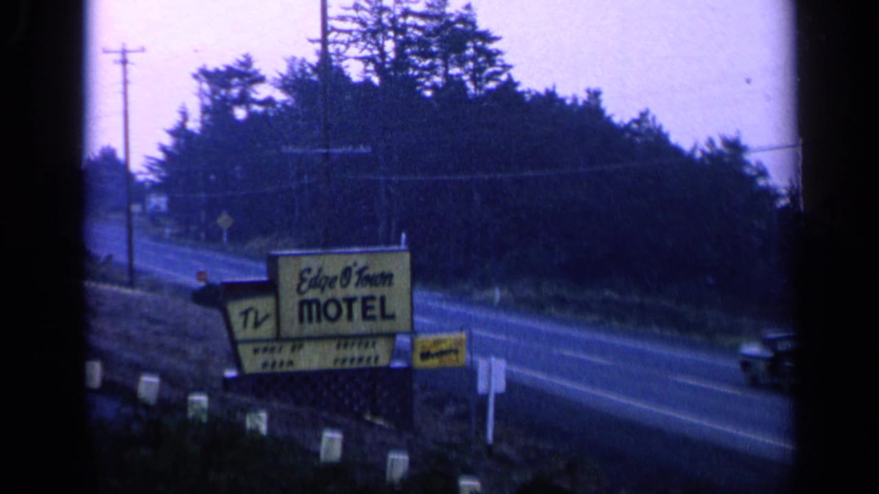 Yellow Edge O' Town Motel sign beside a two-lane road with trees and utility poles.