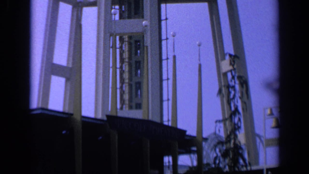 Low-angle view of a geometric tower with a dark roofline and purple sky.
