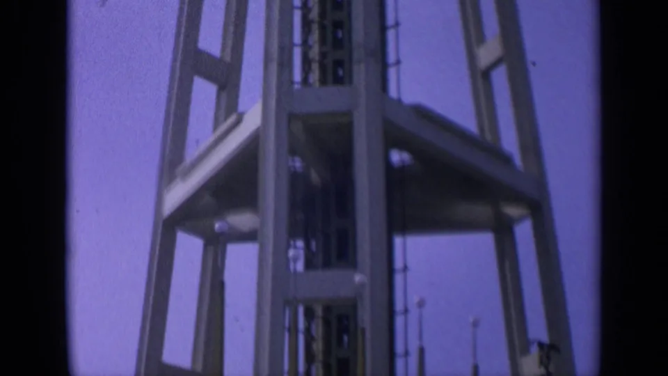 1963 California 8mm frame showing the lower tower platform, open supports, and central core during the upward pan.