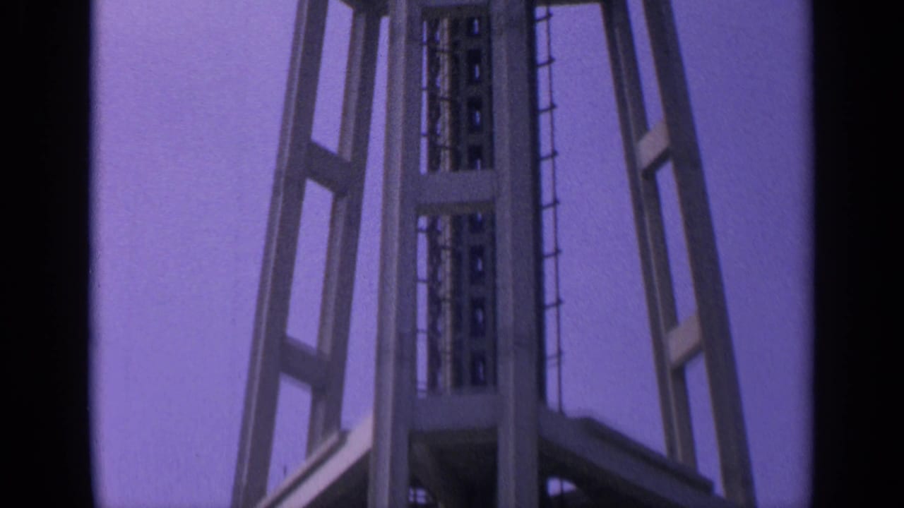 Low-angle view of a tall steel tower section against a purple sky.