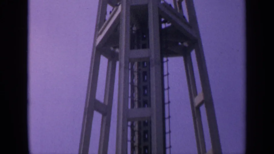 1963 California 8mm frame showing an upper tower section with ladder access, platform framing, and open steel supports.