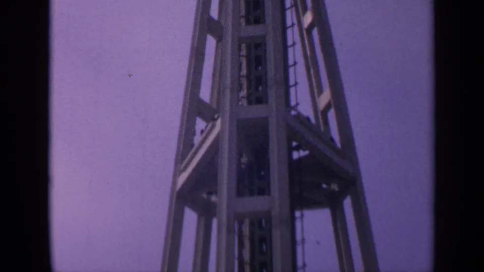 1963 California 8mm frame showing the tower shaft, ladder, and braced platform area from a close upward angle.