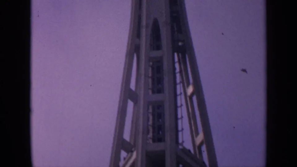1963 California 8mm frame showing a tall steel framework, ladder, and platform details against a purple-tinted sky.