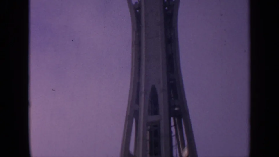 The Space Needle appears partly cropped as the camera continues upward against a dusky purple sky.