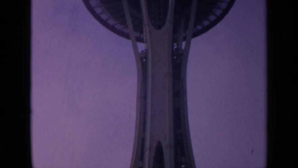 Low-angle 8mm view of the Space Needle observation deck and central shaft beneath a purple sky.