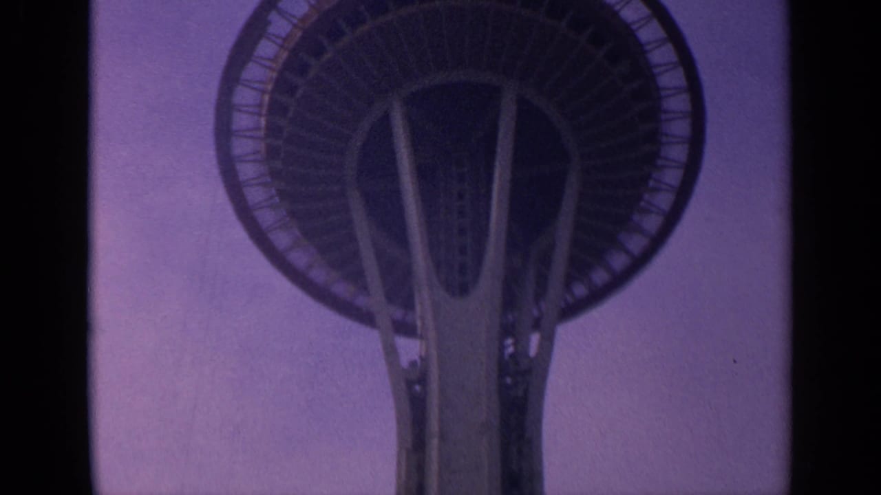 Low-angle view of the Space Needle crown against a purple sky.