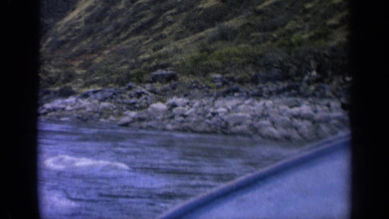 Rocky shoreline and rippled water seen from a moving boat.