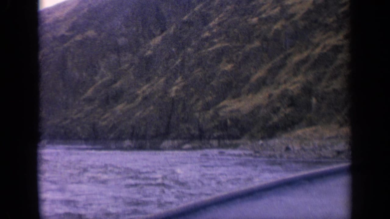 Mountain river and rocky shoreline with dark vertical film border.