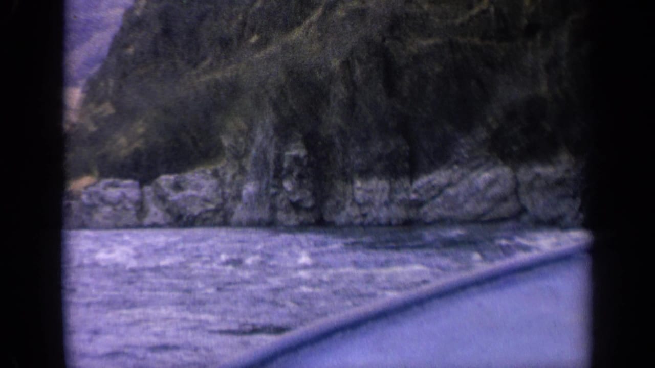 River water and rocky canyon wall viewed from a moving boat.