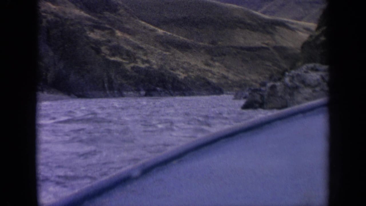 1963 Idaho mountain-road footage frames a river and rocky canyon slope through an 8mm contact-sheet scan.