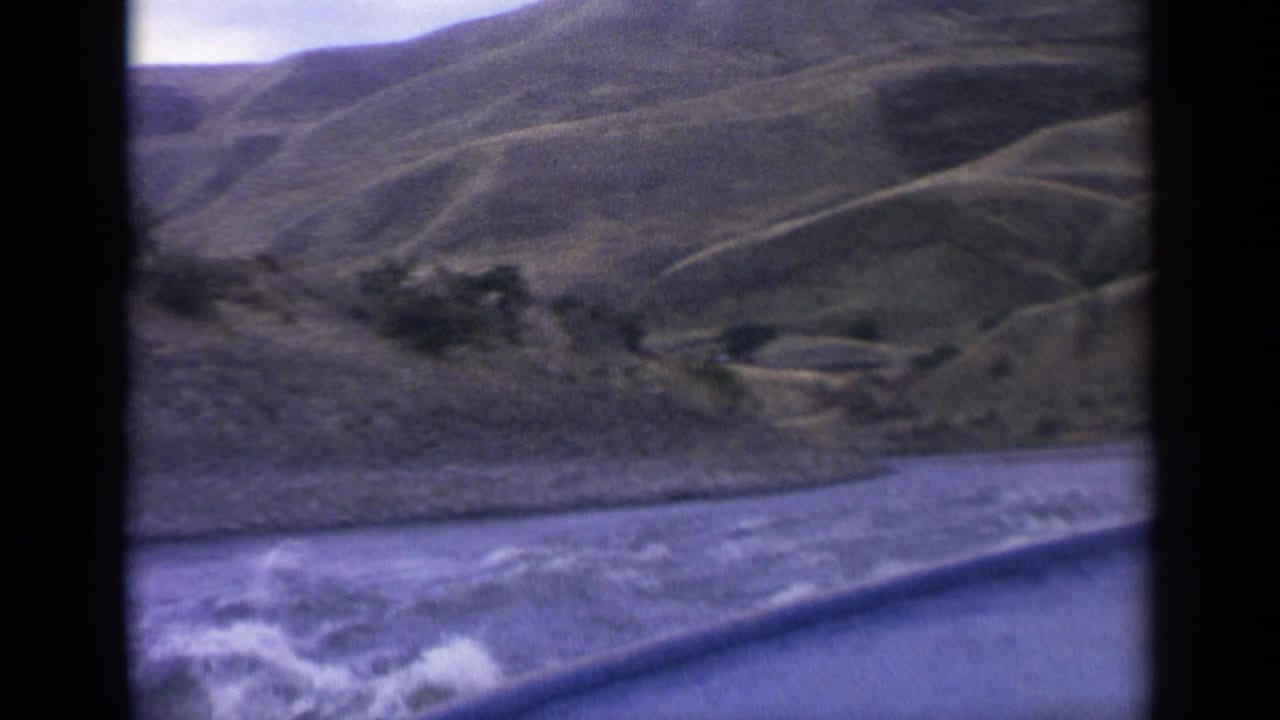 Forward boat view with river spray, hillside slopes, and a dark frame divider.