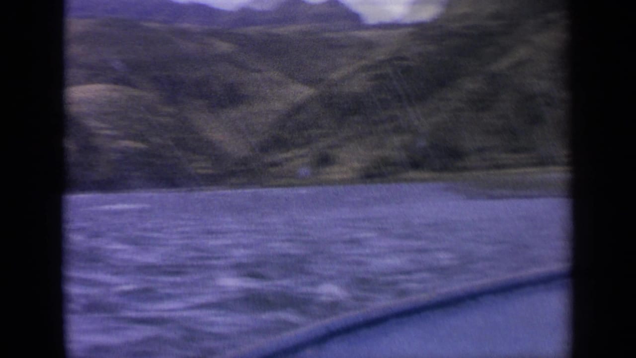Boat edge in the foreground with rough water and hills in the distance.