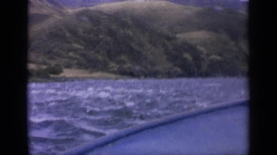 8mm Idaho travel frame from 1963 showing a low boat-side view over rippled water toward a hillside.