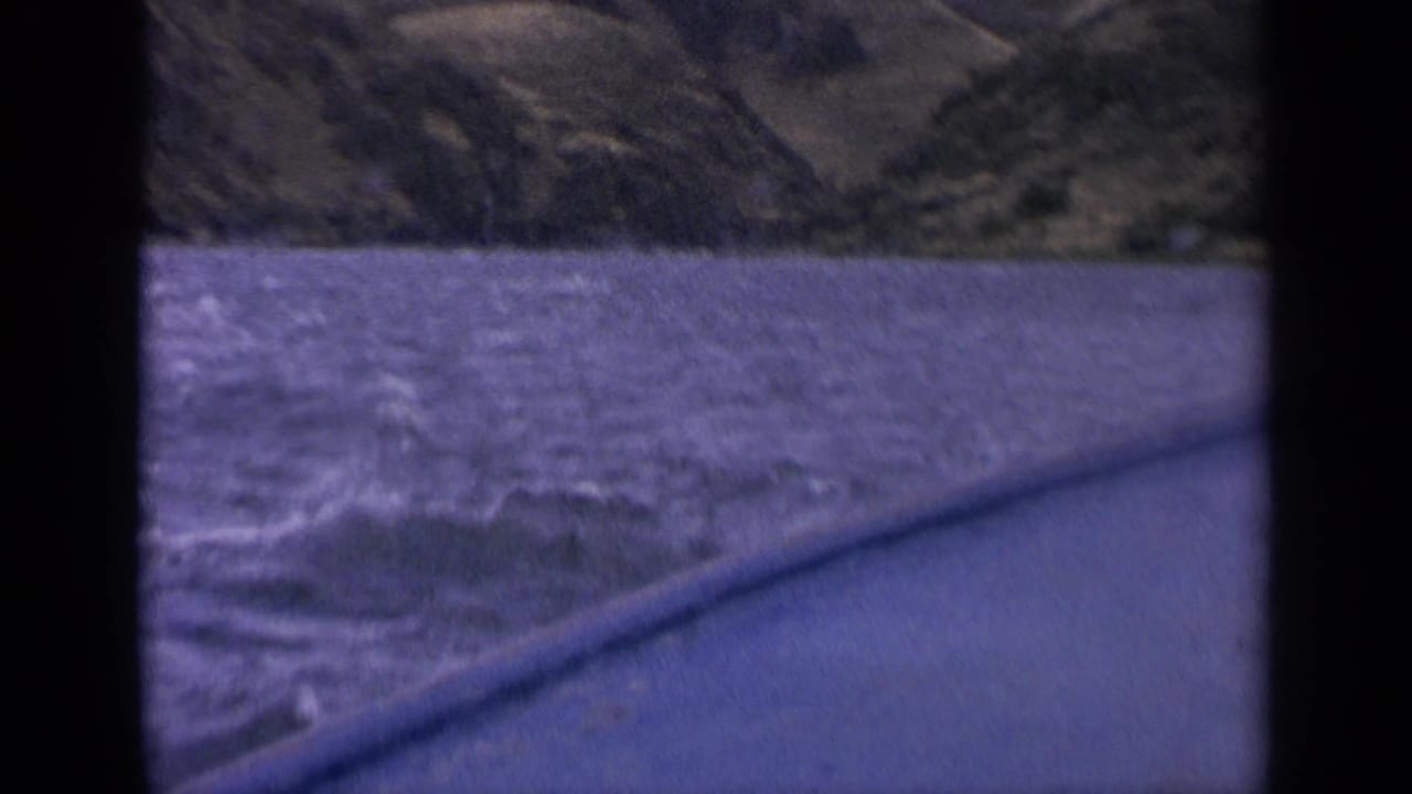 Rippling lake surface beside a boat with hills across the water.