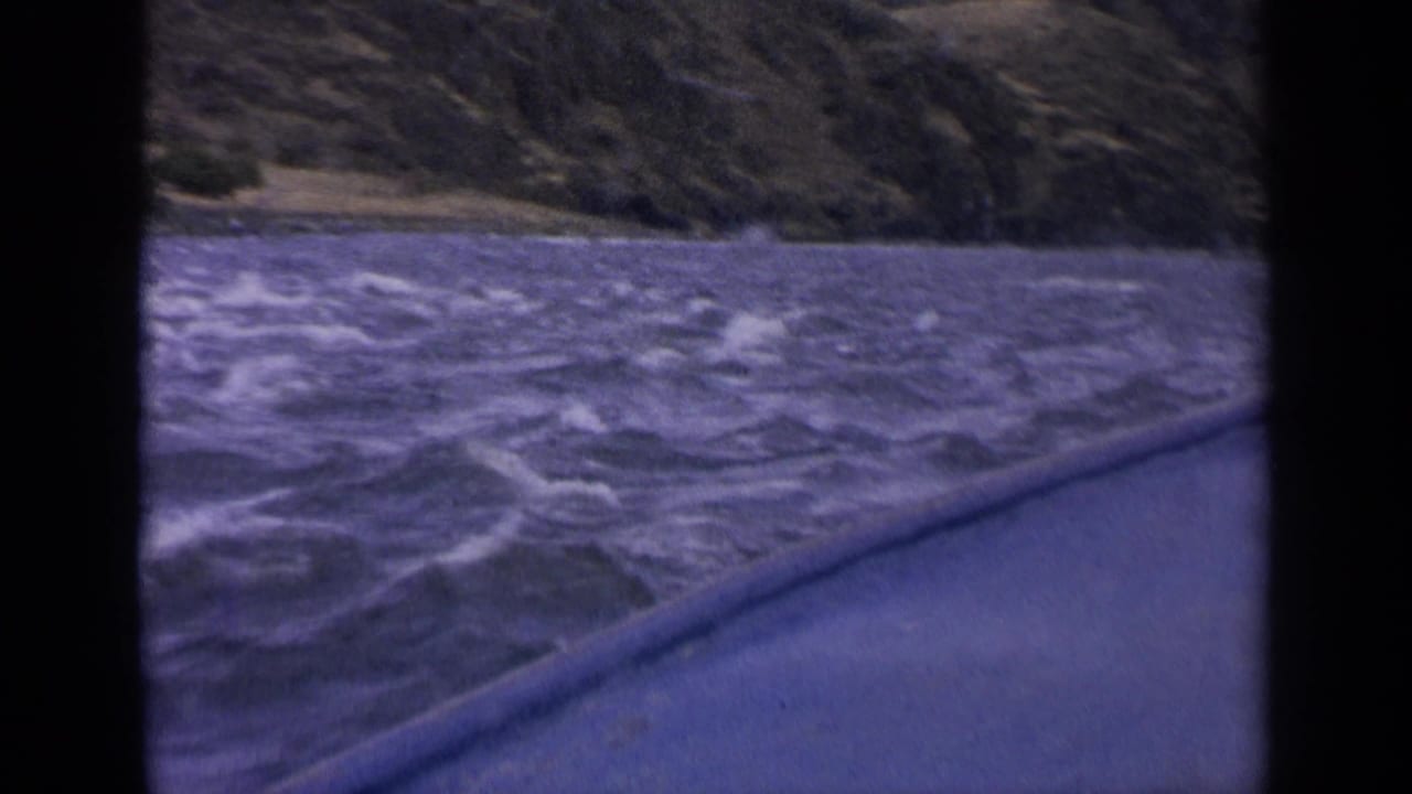 1963 Idaho 8mm frame showing rough purple-tinged lake water, whitecaps, and hills from a boat-level viewpoint.