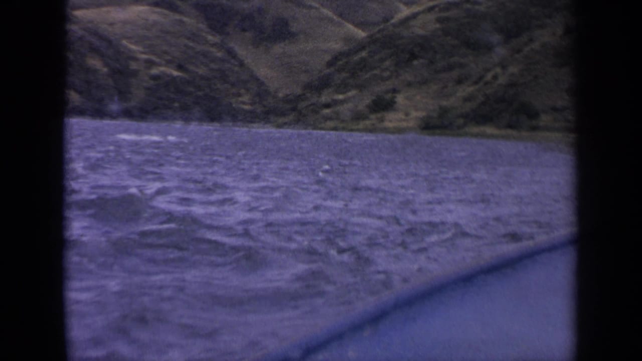 Waves and whitecaps fill the foreground with a sloped mountain shoreline beyond.