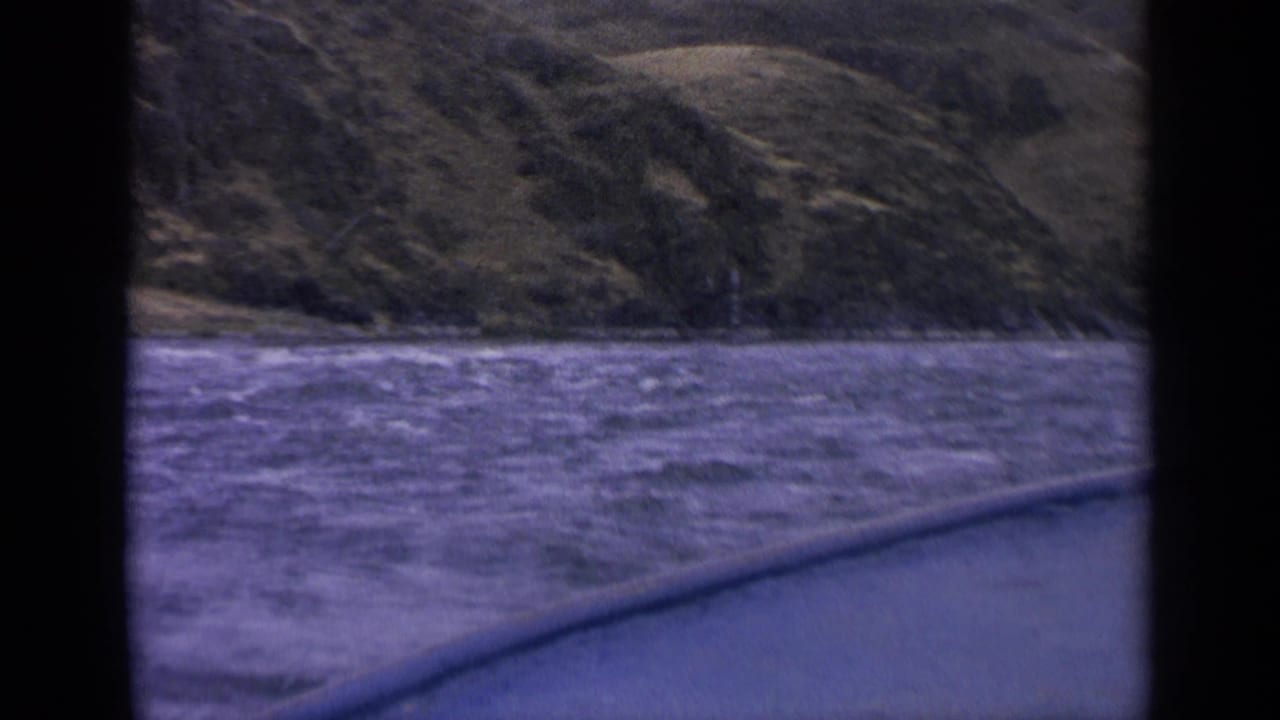 Choppy lake water and rugged hillside seen from a moving boat with dark frame edges.