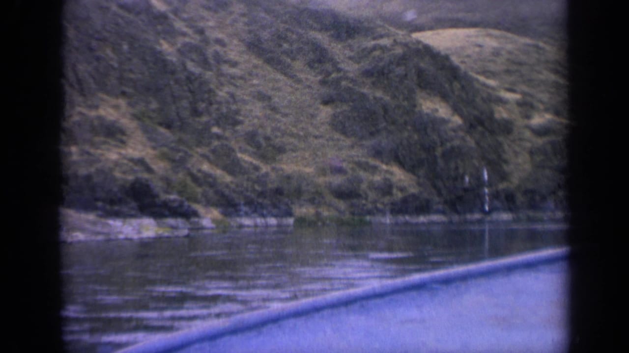 Mountain shoreline reflected in calm water with a blue foreground edge across the lower frame.