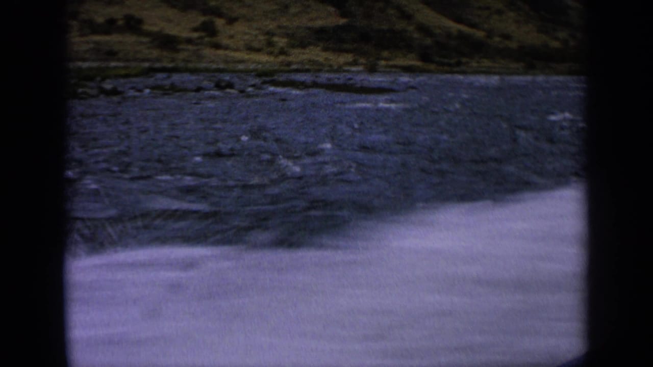 Choppy blue river water beside a grassy hillside, with dark 8mm frame borders.