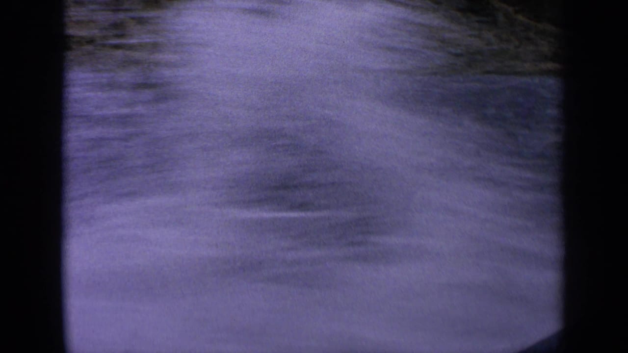 Soft, motion-blurred 8mm frame of splashing river wake in Idaho, with water and bank detail partly obscured.