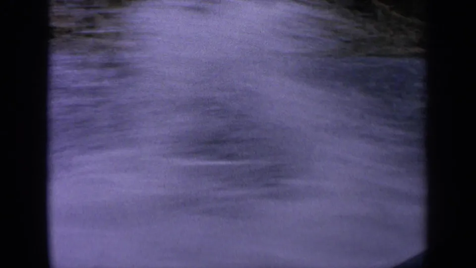 Soft, motion-blurred 8mm frame of splashing river wake in Idaho, with water and bank detail partly obscured.