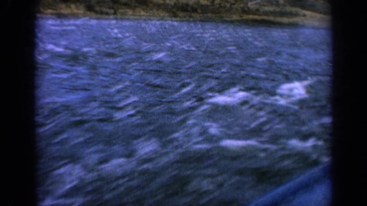 Handheld 8mm view of an Idaho river in 1963, with whitecaps, motion blur, and the boat edge visible at the bottom.
