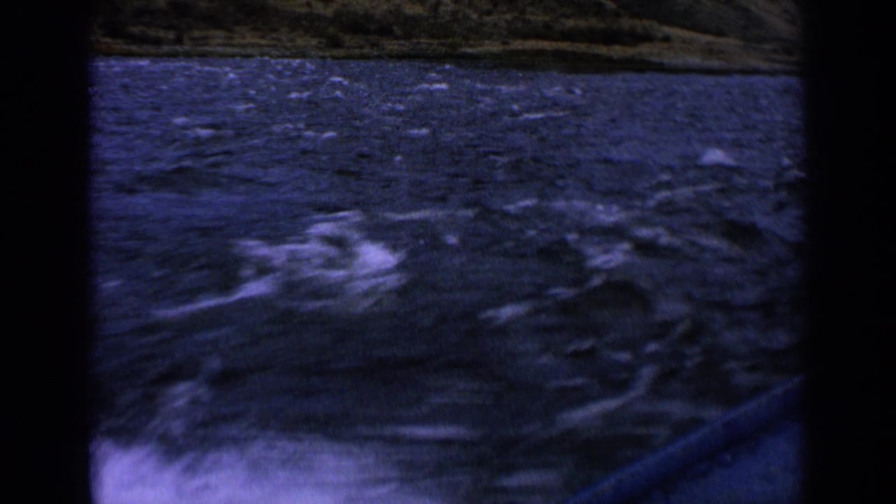 Final 1963 Idaho 8mm frame showing choppy river water, white spray, and a distant grassy bank from a fast-moving boat.