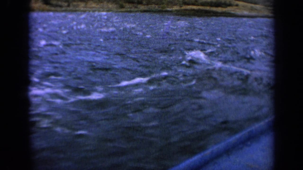1963 Idaho 8mm frame showing choppy blue river water, white wake, and a blurred shore from a fast boat viewpoint.