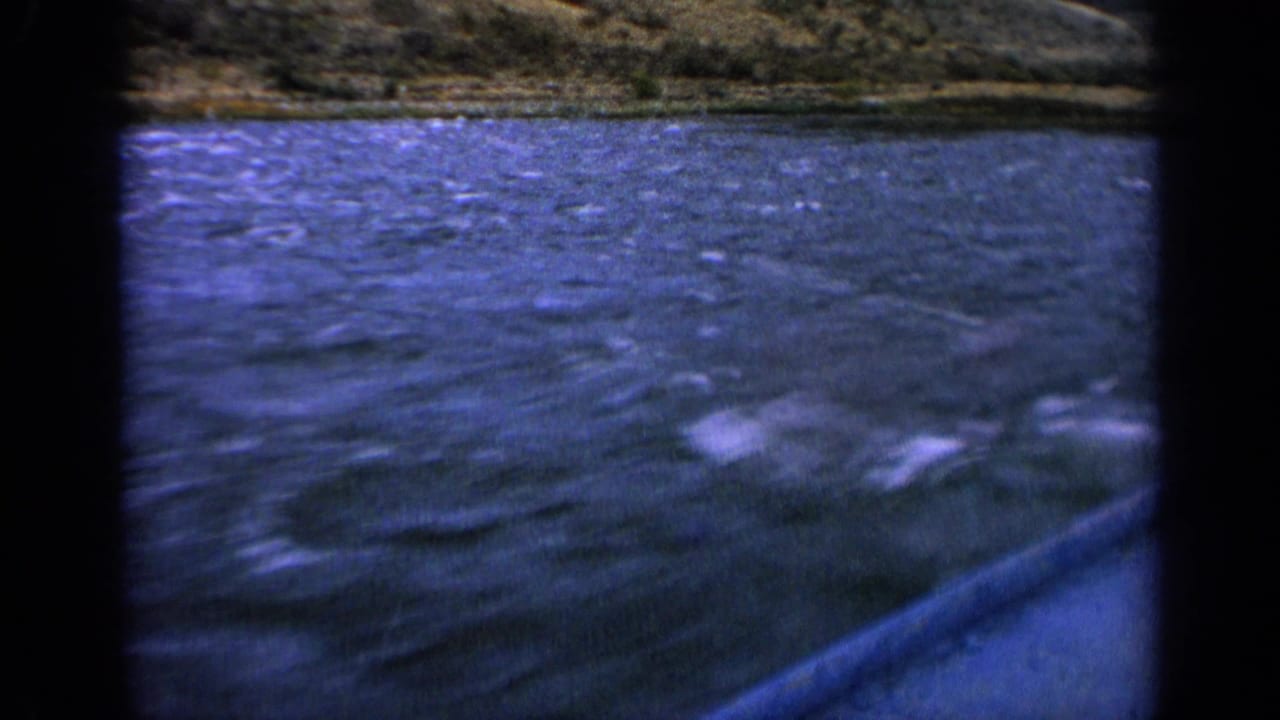 1963 Idaho 8mm frame showing rippling blue lake water and a distant green-brown hillside with soft handheld framing.