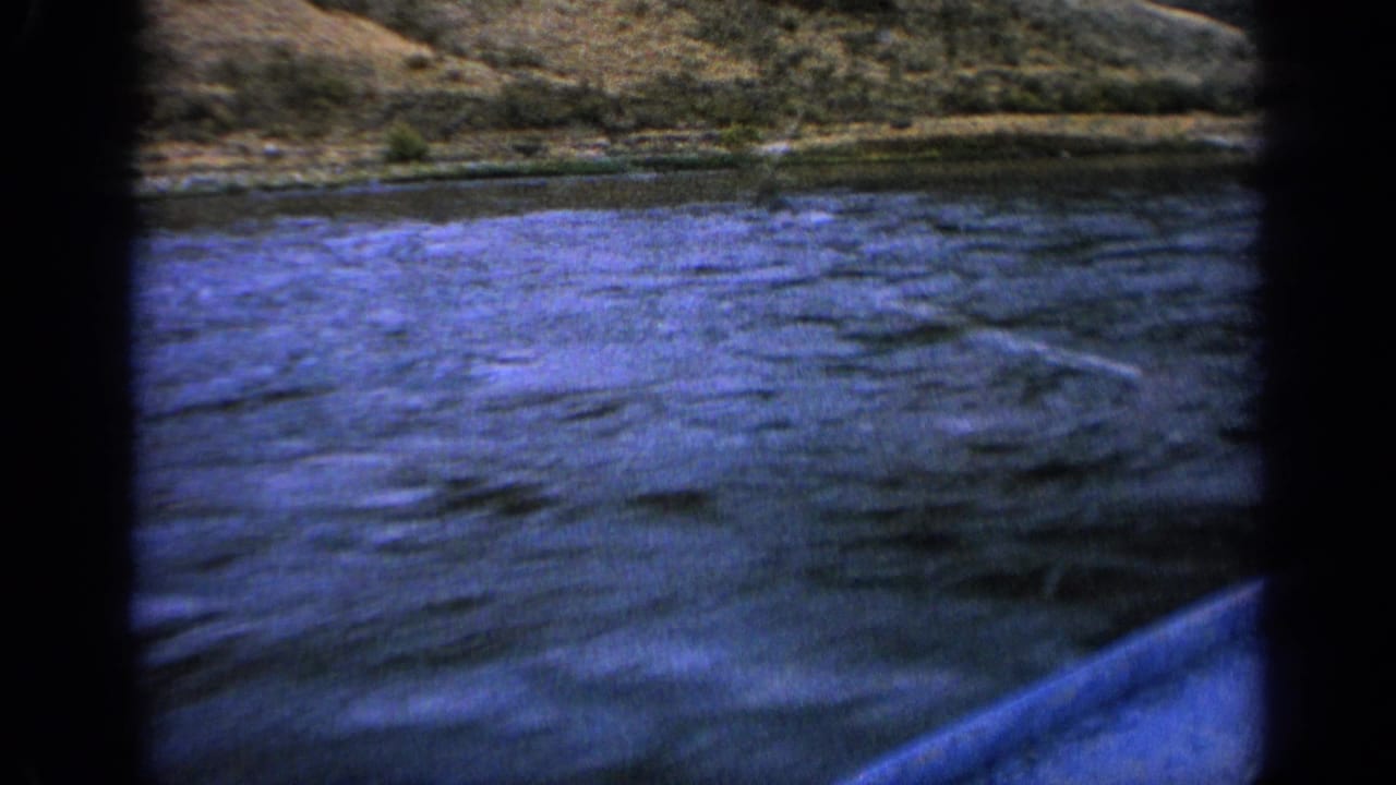 1963 Idaho 8mm frame with blue lake water, distant hillside, and rounded gate edges from the home-movie scan.