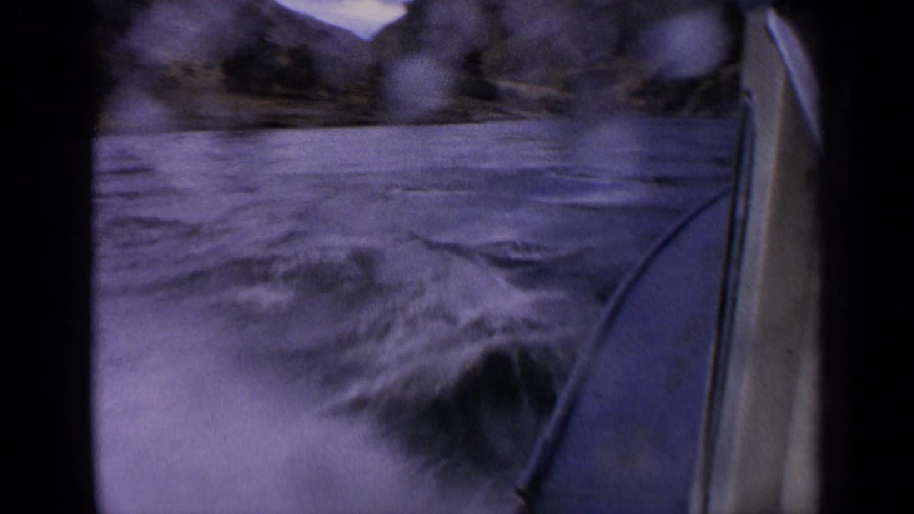 Motion-blurred 1963 Idaho river view from a motorboat, with water spots on the lens and the bow along the right edge.