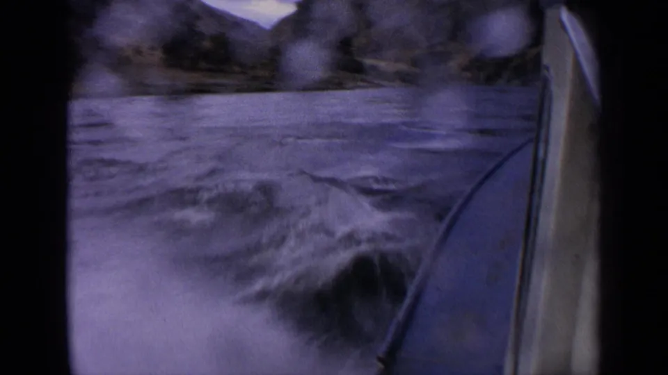 Motion-blurred 1963 Idaho river view from a motorboat, with water spots on the lens and the bow along the right edge.