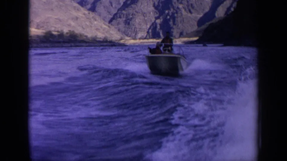 Final 1963 Idaho frame shows the small motorboat farther ahead, with broad wake and rocky canyon terrain around the river.