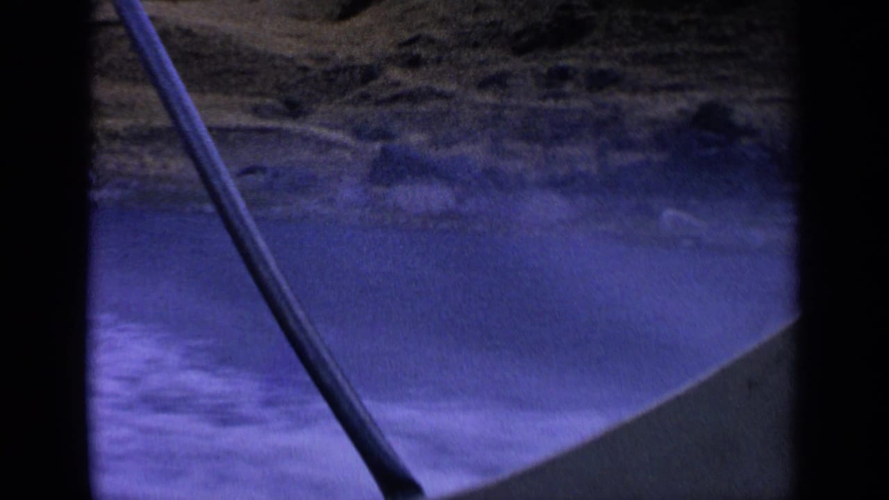Handheld 8mm view from inside a boat on an Idaho desert lake, with wake, shoreline, and a fishing rod crossing the frame.