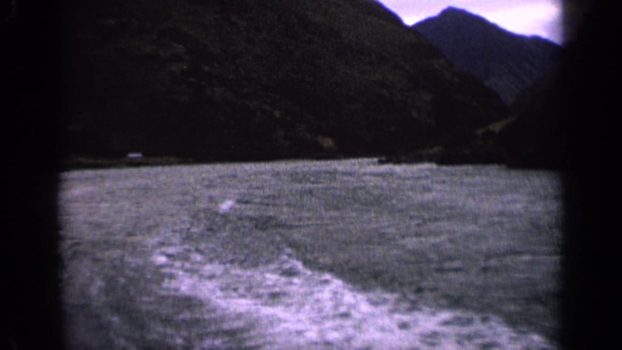 1963 Idaho 8mm frame looking over a moving boat wake toward a broad mountain lake and shadowed slopes.