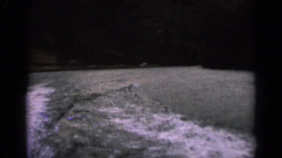 1963 Idaho 8mm frame showing turbulent river water and wake from a moving boat, with dark banks in the background.
