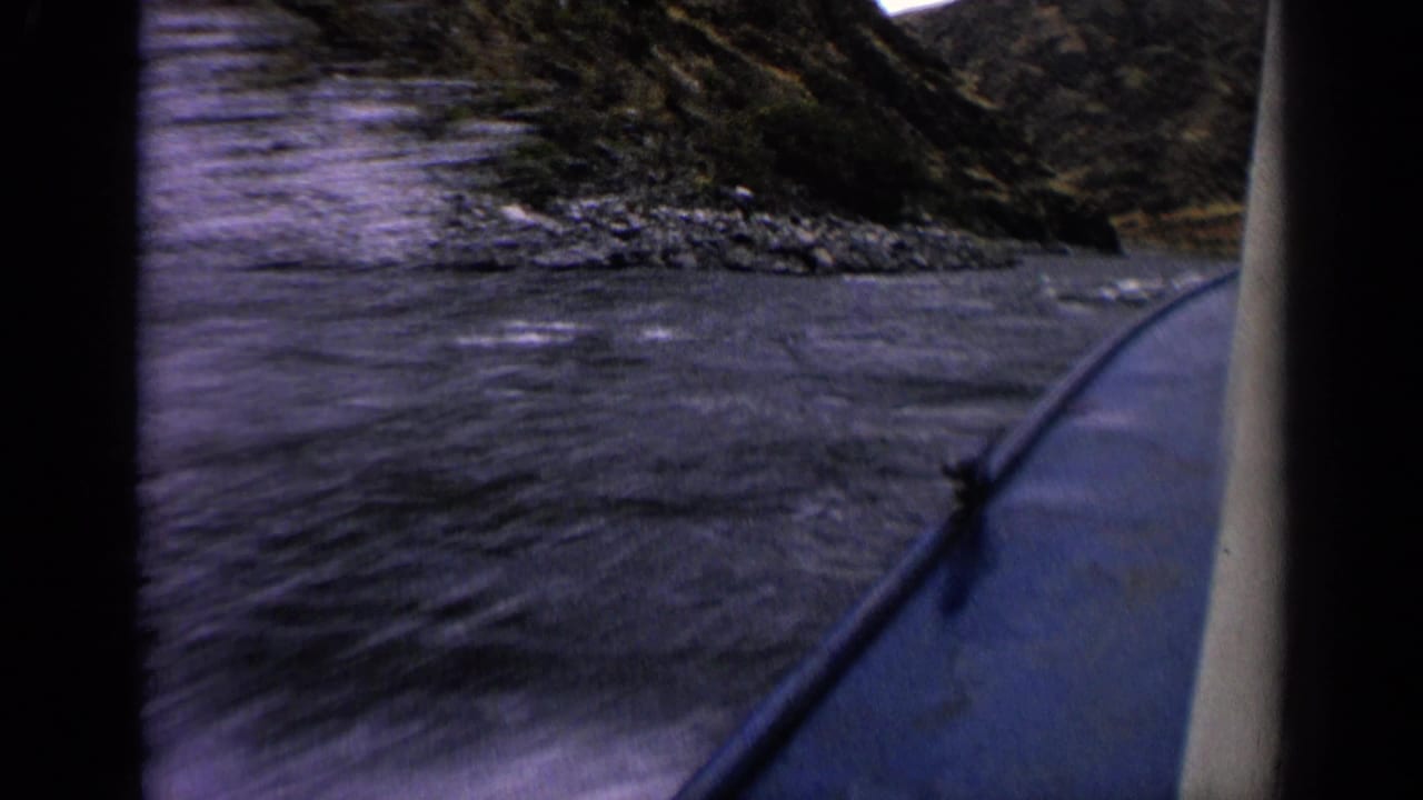 Final 1963 Idaho 8mm frame showing a boat rail, wake in the foreground, and rocky riverbanks ahead.
