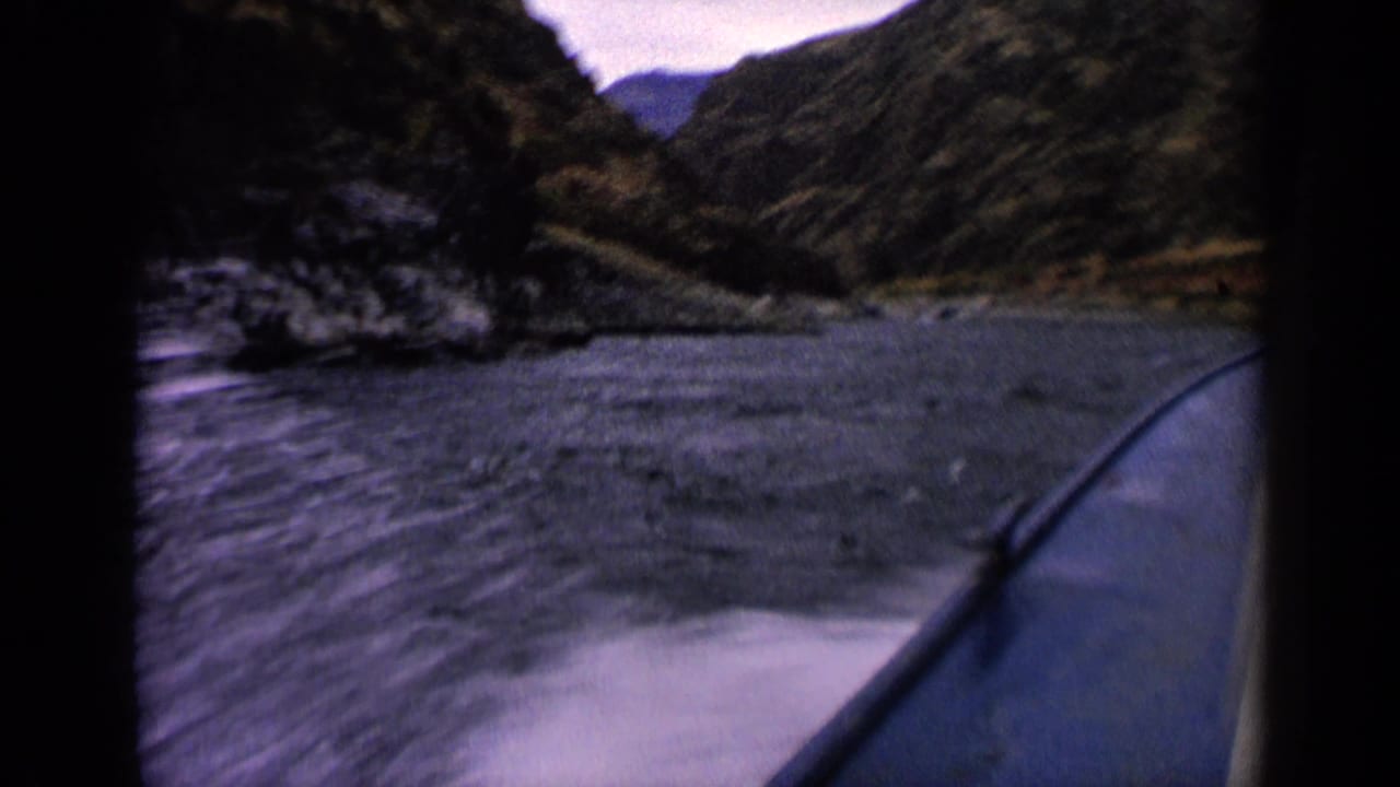 View from a speedboat on an Idaho mountain lake, with rippled water, steep hillsides, and a valley opening in the distance.