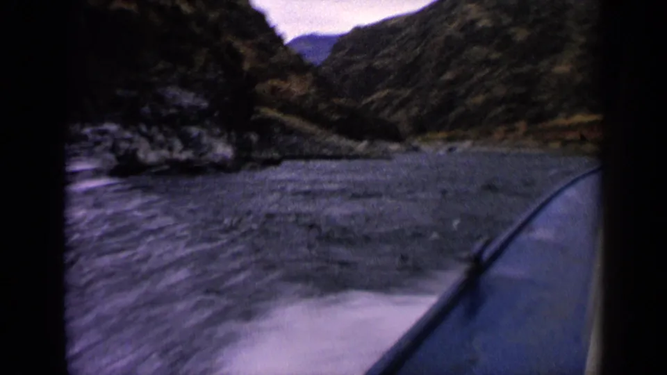View from a speedboat on an Idaho mountain lake, with rippled water, steep hillsides, and a valley opening in the distance.