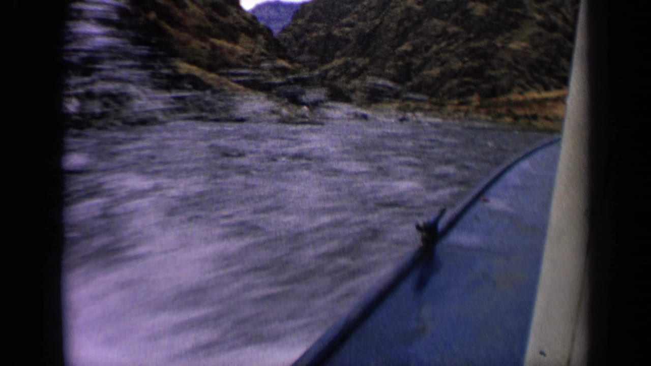 1963 Idaho 8mm view from inside a boat moving through a narrow river with rocky canyon slopes ahead.
