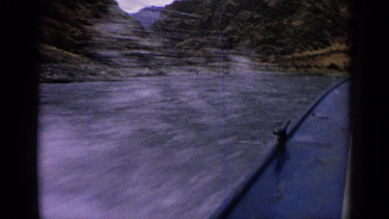 Passenger viewpoint from a 1963 Idaho boat as the bow runs alongside rippling water and canyon walls.