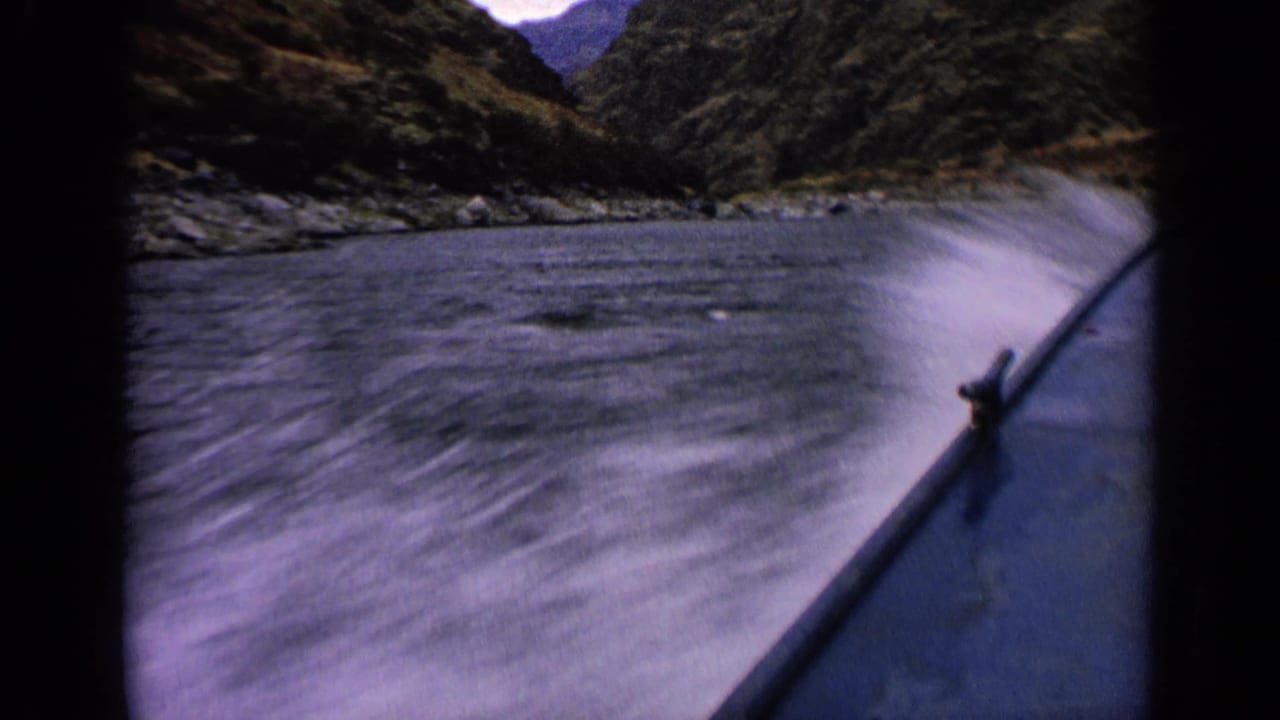 1963 Idaho home-movie frame showing the boat bow kicking up white spray in a rocky river channel.