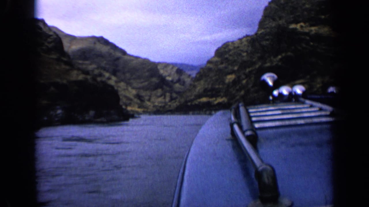 1963 8mm frame of a boat bow and metal fittings seen from a passenger viewpoint on a narrow canyon waterway, likely in Idaho.