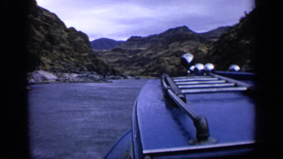 1963 Idaho 8mm boat POV showing rocky shoreline, open water, and layered canyon hills.