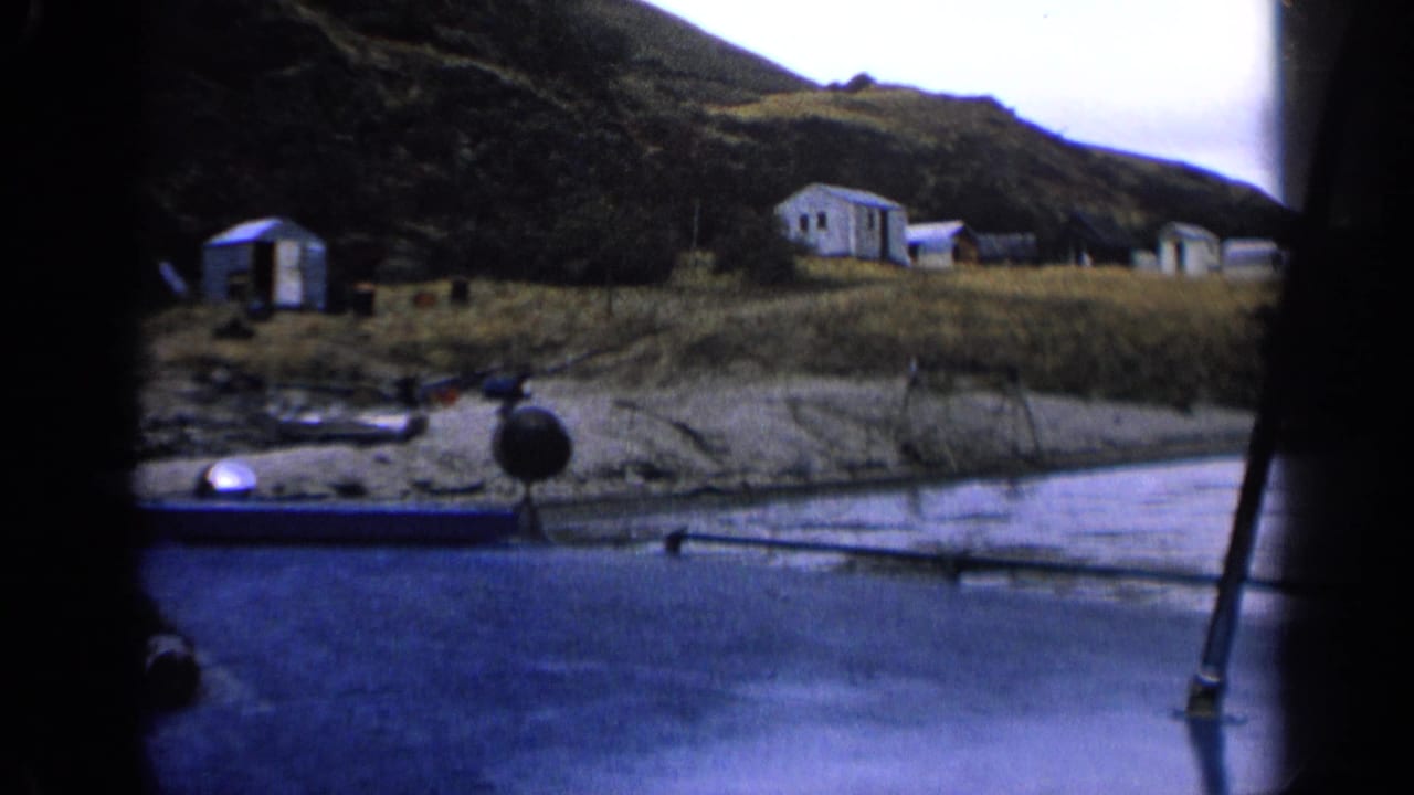 Idaho 1963 8mm frame of modest shoreline buildings and a hillside settlement seen from a moving boat.