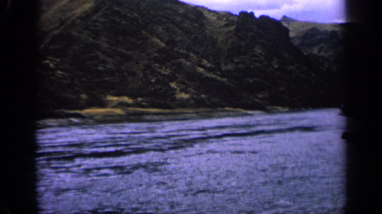 Wide river beside steep rocky hills with dark frame edges.