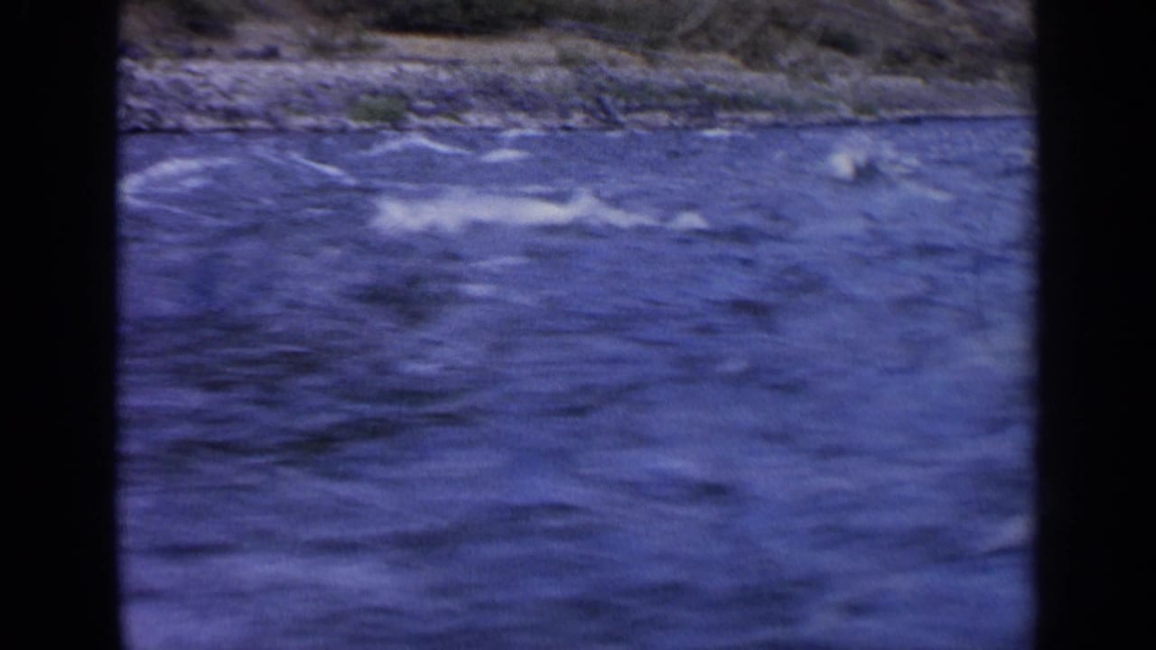 Turbulent blue water with whitecaps beside a rocky shoreline.